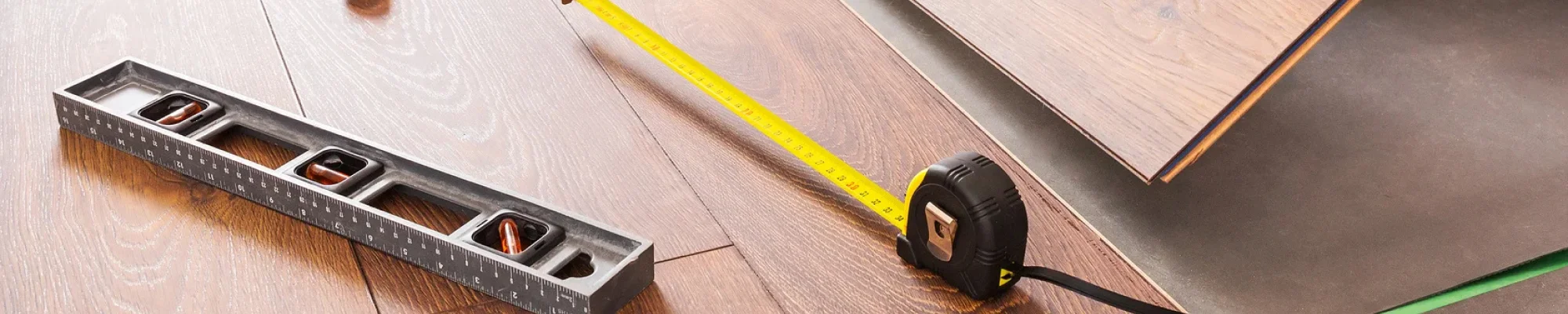 Luxury vinyl plank flooring installation with measuring tape and level