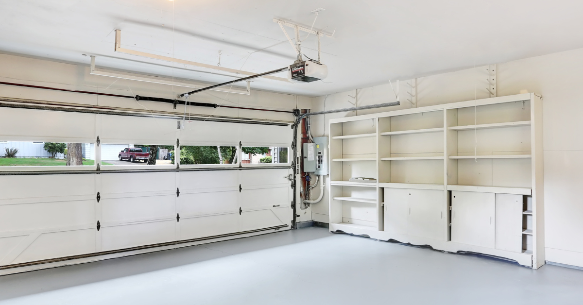 A garage featuring a large white door and organized shelves filled with various tools and storage items.
