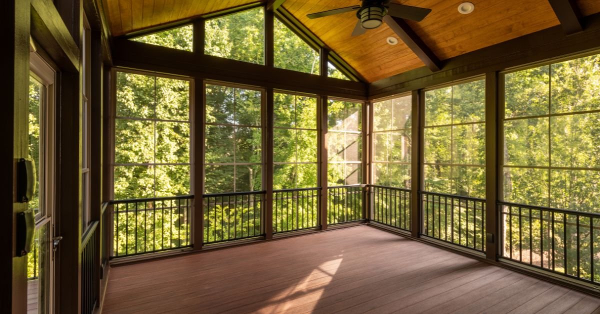 A screened porch featuring wooden floors and large windows, providing a bright and airy outdoor living space.