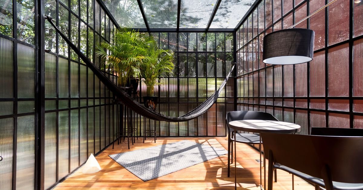 A hammock is suspended in a sunroom featuring a table and chairs, creating a cozy and inviting atmosphere.