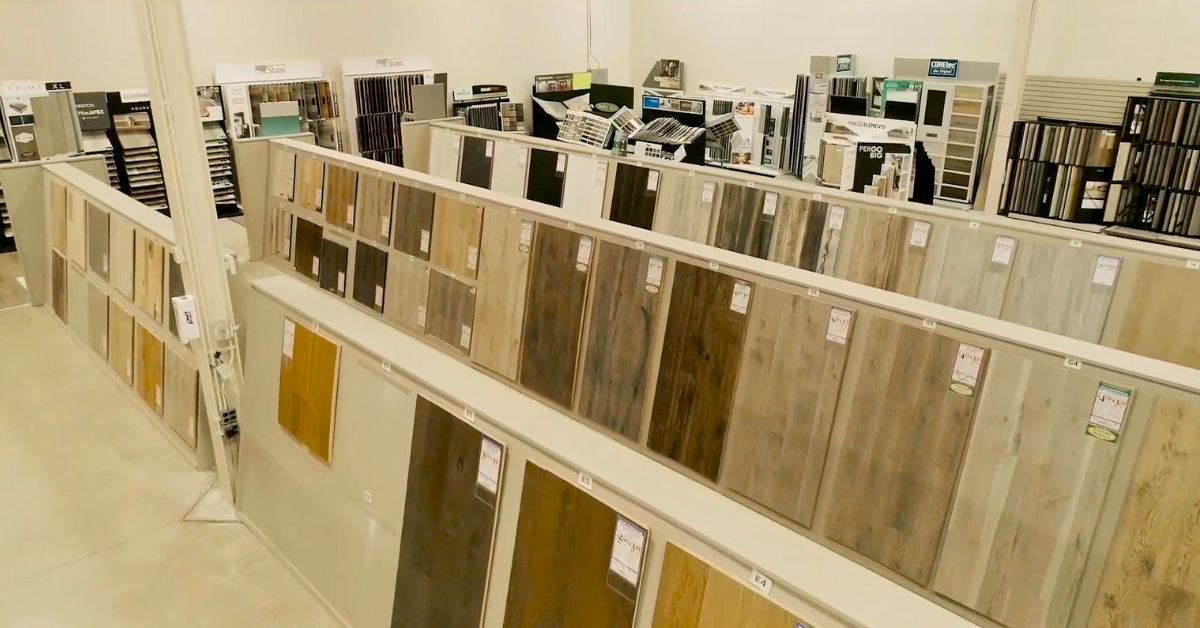 A spacious room showcasing various types of flooring, including wood, tile, and carpet, arranged in distinct sections.